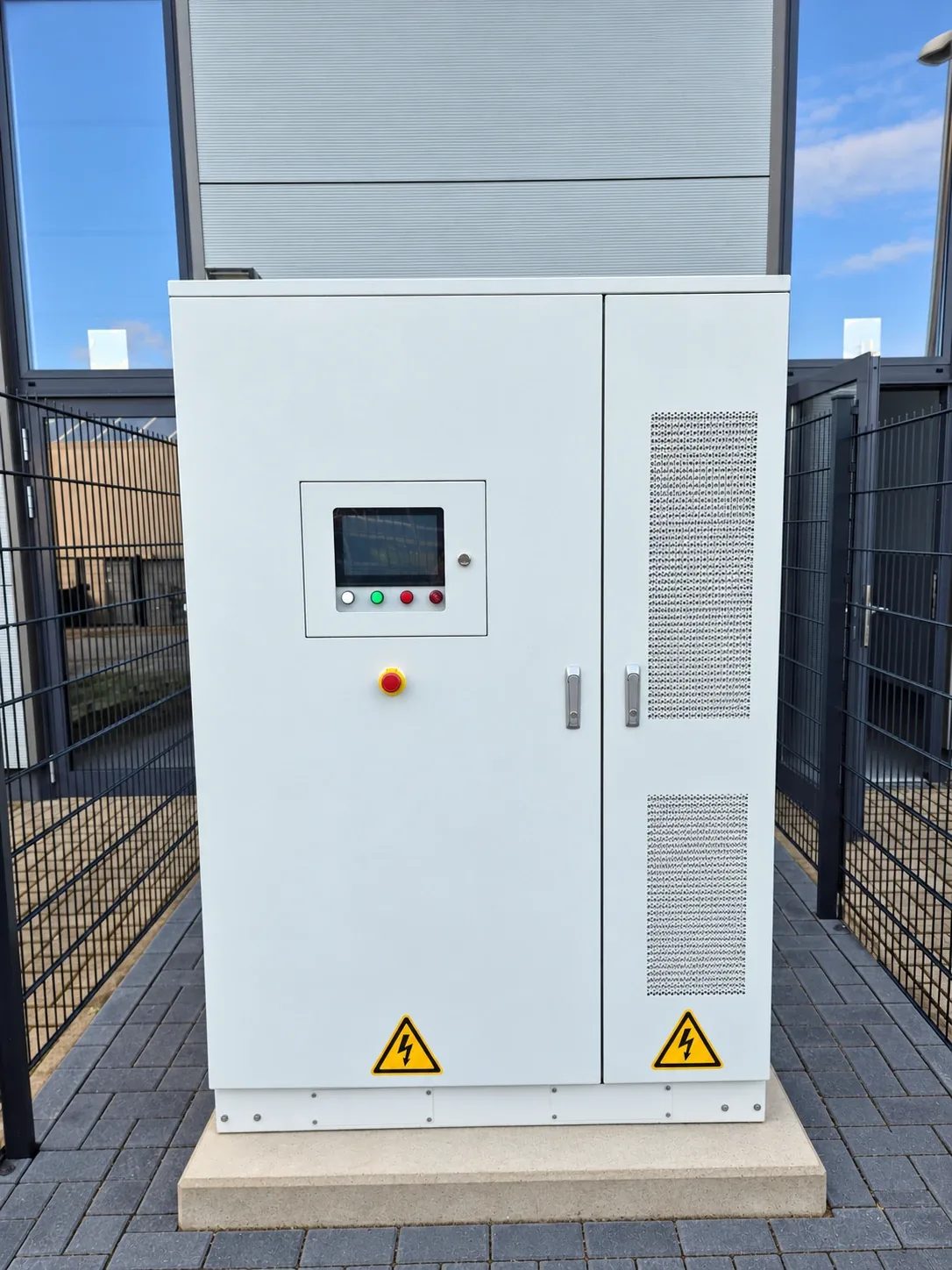 Geschlossener Batteriespeicher am Standort Ibbenbüren in Frontansicht mit Bedienfeld und Not-Halt, aufgestellt auf einem Betonsockel