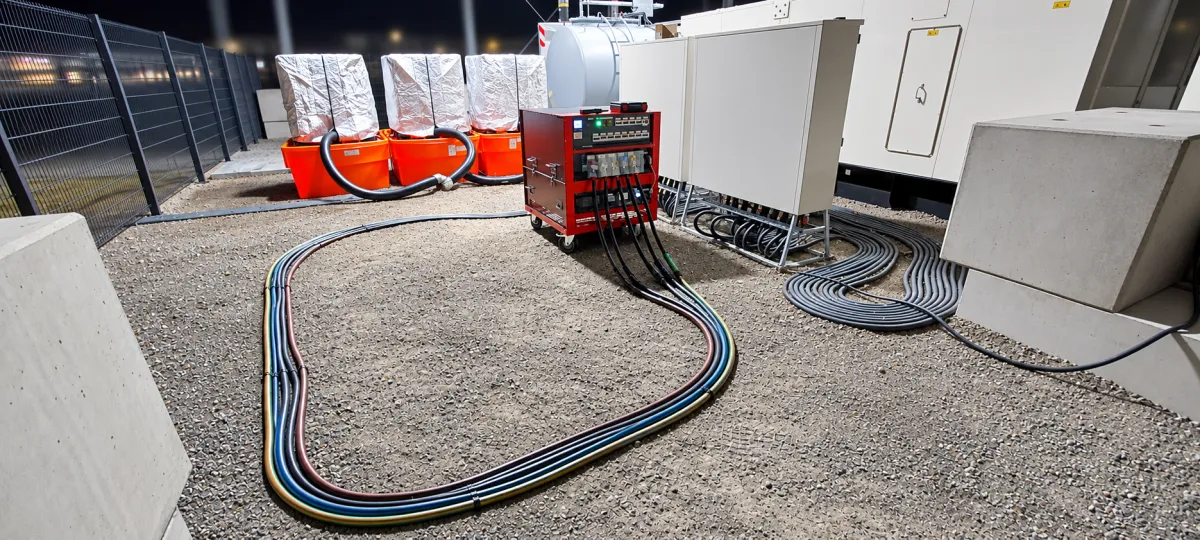 Mobile Lastbank auf Rollen bei Nacht, über farbige Lastkabel an die Anlage angeschlossen