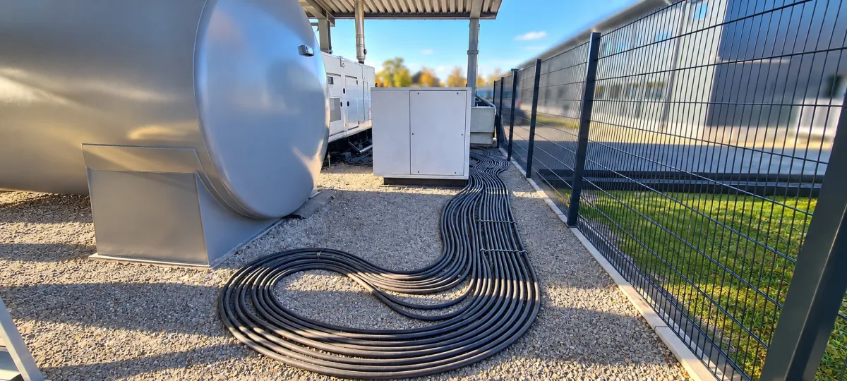 Sauber verlegte Lastkabel auf Kiesfläche zwischen Tank und Schaltschrank bei Tag
