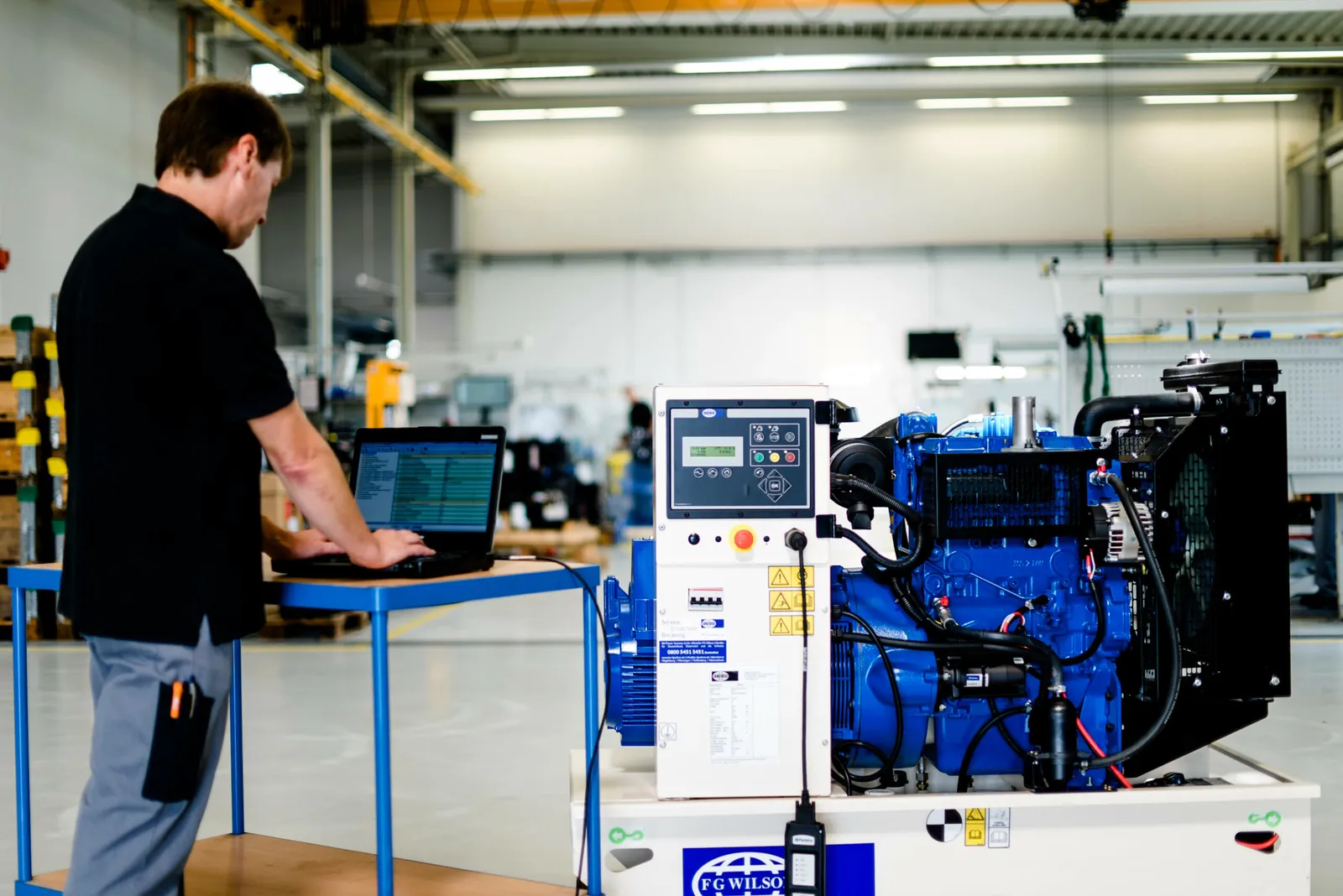 Techniker bei der Wartung eines offenen FG Wilson Diesel-Stromaggregats